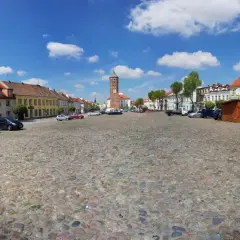 Rynek w Pułtusku z brukowaną nawierzchnią, kolorowymi kamienicami i charakterystyczną wieżą.