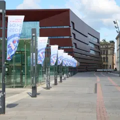 Plac Wolności we Wrocławiu z nowoczesnym budynkiem i rzędem flag.