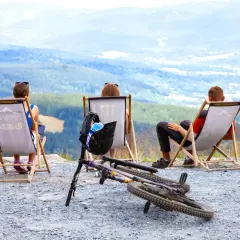 Odpoczynek po zjazdach na Czarna Góra. Widok na góry i miasto, rower i kask czekają na kolejną przygodę.