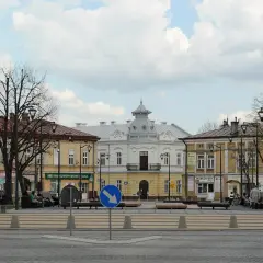 Rynek w Mielcu z kamienicami i ludźmi odpoczywającymi na ławkach. Idealne miejsce na mieleckie atrakcje na weekend.