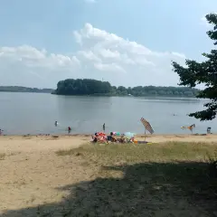Na Jeziorze Przeczyckim można się kąpać. Ludzie odpoczywają na plaży i w wodzie, ciesząc się letnim dniem.