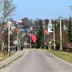 Droga prowadzi do malowniczej wsi Krynki. W oddali widać kolorowe dachy domów i kościół, tworząc urokliwe krynki atrakcje.