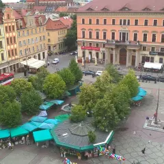 Kolorowe kamienice otaczają plac solny we Wrocławiu, gdzie zielone stragany oferują kwiaty i pamiątki.