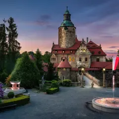 Zamek Czocha o zmierzchu, z fontannami i kwitnącymi rododendronami. Odkryj atrakcje w okolicy tego malowniczego miejsca.