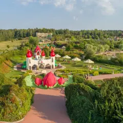 Bajkowy zamek i plac zabaw, gdzie są magiczne ogrody. Dzieci bawią się wśród zieleni i kwiatów.