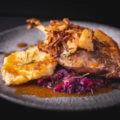 Pieczona kaczka z dodatkami: plackiem ziemniaczanym, czerwoną kapustą i chrupiącą cebulką.