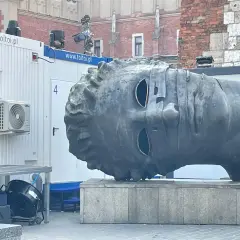 Monumentalna głowa na rynku w Krakowie, z pustymi oczodołami, wygląda jakby patrzyła w dal.