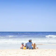 Dzieci bawią się na plaży z widokiem na spokojne morze i błękitne niebo.