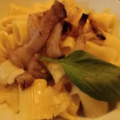 Pyszna carbonara z chrupiącym boczkiem, makaronem rigatoni i listkiem bazylii. Idealny boczek do carbonary to klucz do sukcesu.