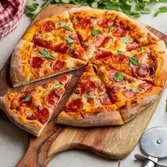 Krojona pizza pepperoni z serem i bazylią na drewnianej desce.