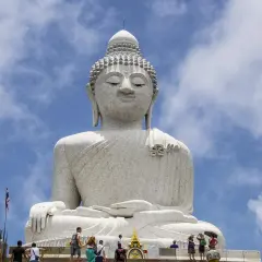 Wielki Budda na Phuket, majestatyczna biała statua na tle błękitnego nieba z chmurami. Turyści wchodzą po schodach.