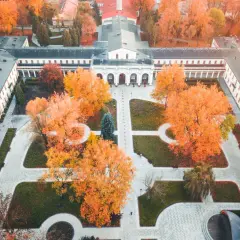 Widok z lotu ptaka na zabytkowy budynek z arkadami otoczony jesiennymi drzewami w Busku-Zdroju.