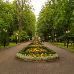 Piękny deptak w Polanicy Zdroju z klombami pełnymi kolorowych kwiatów i alejkami wśród zieleni.