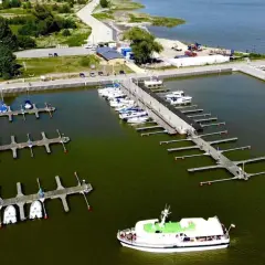 Widok z lotu ptaka na port w Krynicy Morskiej z licznymi łodziami i żaglówkami przy pomostach.