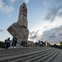 Uroczystość przy Pomniku Obrońców Wybrzeża na Westerplatte. W tle monumentalny monument, a na schodach delegacje i żołnierze.