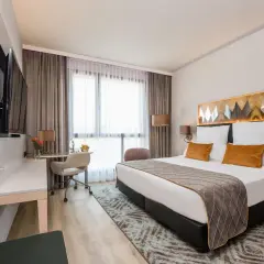 Nowoczesny pokój hotelowy z dużym łóżkiem, biurkiem i telewizorem.