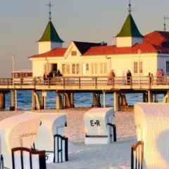 Zachód słońca nad morzem, molo z budynkiem i restauracją, plaża z koszami. Ahlbeck atrakcje zachęcają do spacerów.