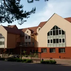 Budynek o ciepłej, pomarańczowej elewacji, przypominający kształtem bocheniec chleba, z dużymi, nowoczesnymi oknami.