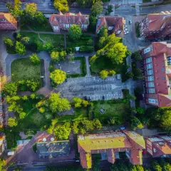 Widok z lotu ptaka na zabudowania i tereny zielone. Widać parking, budynki z czerwonymi dachami i drzewa. Promenada Świnoujście atrakcje w pełnej krasie.