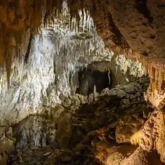 Wnętrze jaskini z naciekami skalnymi i kamienistym dnem.