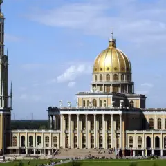Bazylika w Licheniu z wysoką wieżą i złotą kopułą na tle błękitnego nieba.