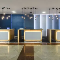 Recepcja hotelowa z trzema ladami, nowoczesnymi lampami i podświetlanymi panelami.