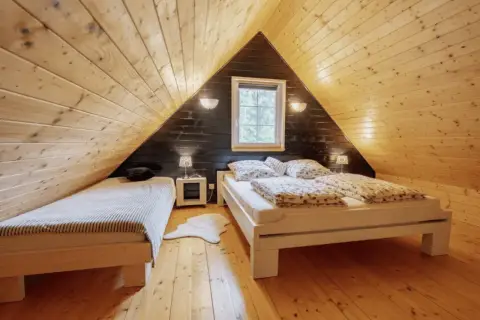 Przytulne, klimatyczne domki w lesie. Drewniane wnętrze z dwoma łóżkami, okienkiem i lampkami nocnymi.