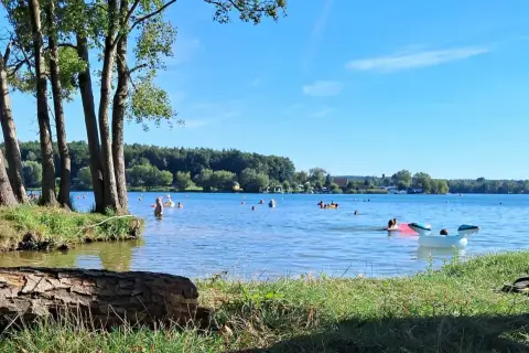 Słoneczny dzień nad jeziorem Pławniowice. Ludzie kąpią się i relaksują na dmuchanych zabawkach.