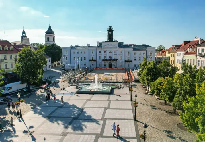 Stary Rynek Płock z ratuszem i fontanną w centrum. W tle widać kościoły i kolorowe kamienice.