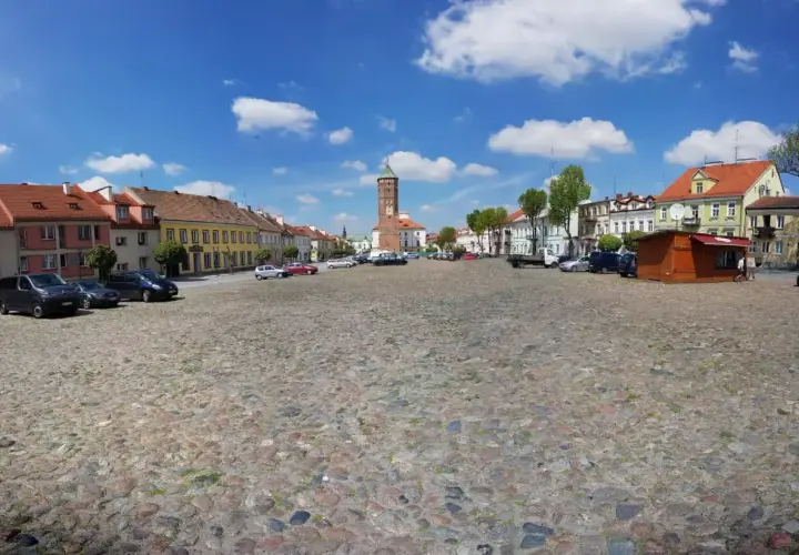 Rynek w Pułtusku z brukowaną nawierzchnią, kolorowymi kamienicami i charakterystyczną wieżą.
