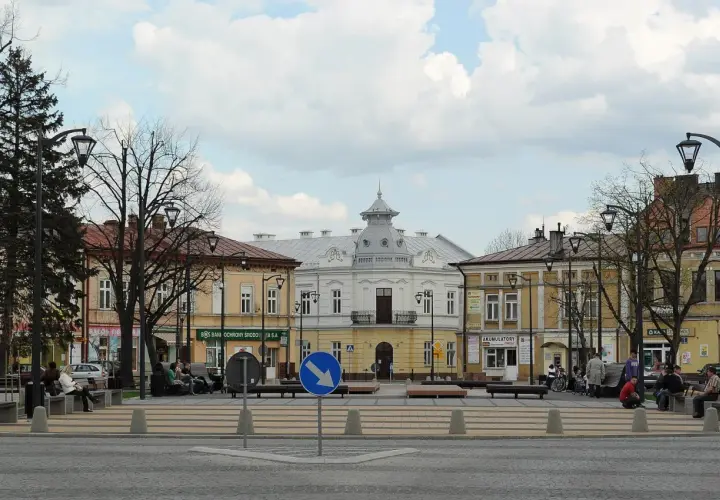 Rynek w Mielcu z kamienicami i ludźmi odpoczywającymi na ławkach. Idealne miejsce na mieleckie atrakcje na weekend.