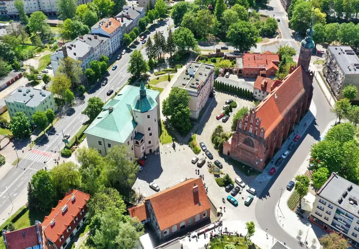 Słupsk atrakcje na weekend: zamek Książąt Pomorskich i kościół Mariacki z lotu ptaka. Zielone dachy i czerwona cegła tworzą malowniczy widok.
