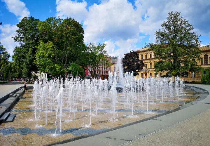 Plac Litewski w Lublinie tętni życiem, a fontanny tworzą wodny taniec na tle zabytkowych kamienic.