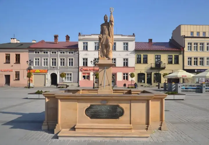 Pomnik na żywiec rynku, z kolorowymi kamienicami w tle.