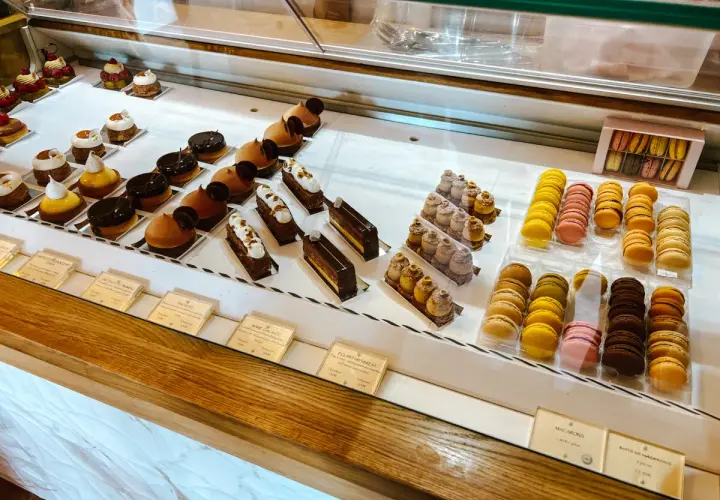 Witryna cukierni z wykwintnymi deserami, w tym makaronikami i ciastkami, idealna dla szukających najlepszych francuskich restauracji.
