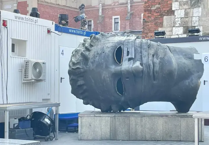 Monumentalna głowa na rynku w Krakowie, z pustymi oczodołami, wygląda jakby patrzyła w dal.
