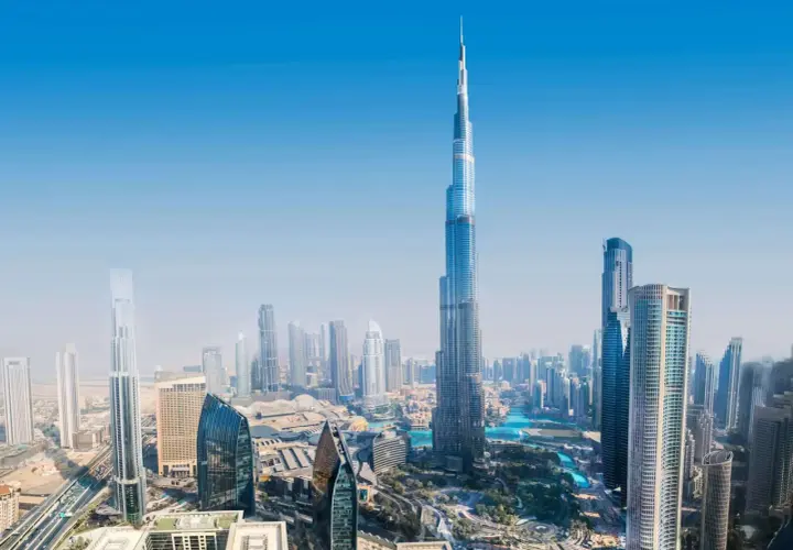 Widok z lotu ptaka na Dubaj, z dominującym Burdż Chalifa. Nowoczesne drapacze chmur i błękitne wody tworzą futurystyczny krajobraz.