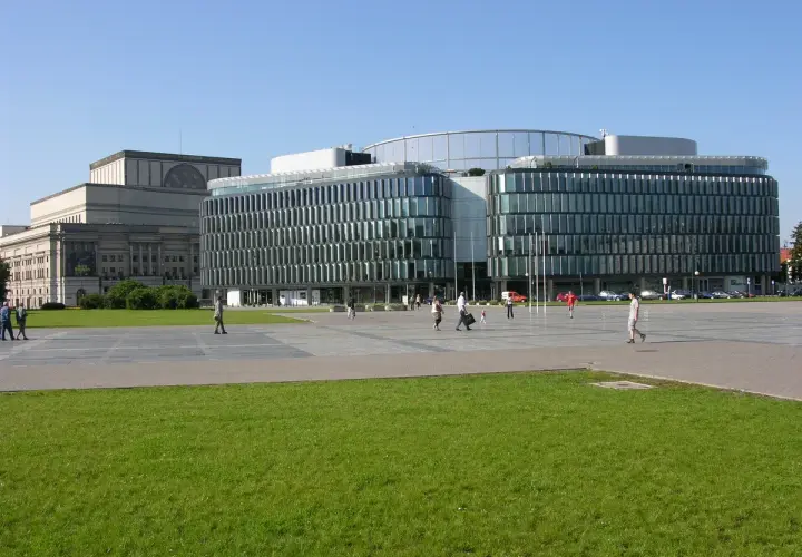 Plac Piłsudskiego w Warszawie. Nowoczesny budynek z przeszkloną fasadą obok klasycystycznego gmachu.