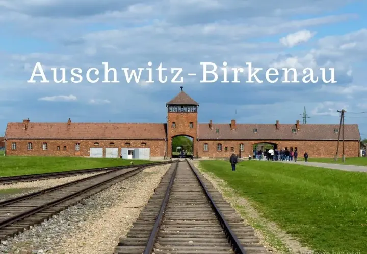 Brama obozowa Auschwitz-Birkenau z wieżą i torami kolejowymi.