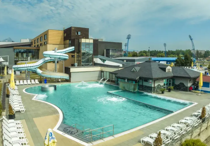 AquaCity Poprad: baseny, zjeżdżalnie wodne i leżaki pod błękitnym niebem.