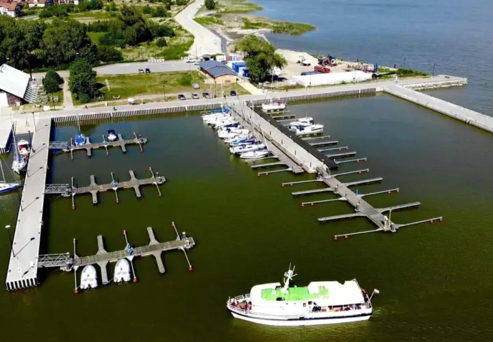 Widok z lotu ptaka na port w Krynicy Morskiej z licznymi łodziami i żaglówkami przy pomostach.