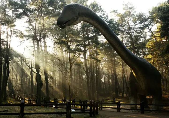 Dinozaur w lesie, jedna z atrakcji Solca Kujawskiego, w promieniach słońca.