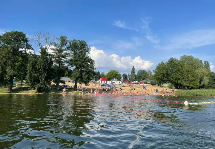 Słoneczny dzień nad jeziorem, pełnym ludzi kąpiących się i opalających. To jedne z fajnych miejsc nad wodą mazowieckie.