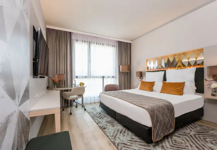 Nowoczesny pokój hotelowy z dużym łóżkiem, biurkiem i telewizorem.