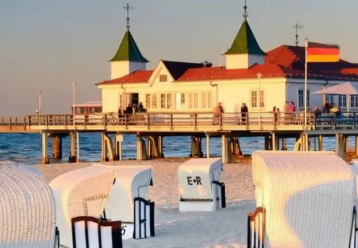 Zachód słońca nad morzem, molo z budynkiem i restauracją, plaża z koszami. Ahlbeck atrakcje zachęcają do spacerów.