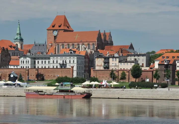 Widok na średniowieczny zespół miejski Torunia z Wisły, z katedrą i ceglanymi murami.