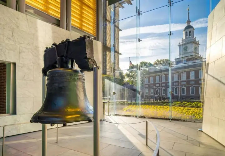 Liberty Bell w nowoczesnym wnętrzu, z widokiem na Independence Hall i kwitnące kwiaty.
