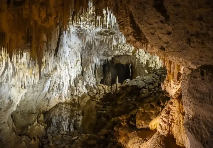 Wnętrze jaskini z naciekami skalnymi i kamienistym dnem.