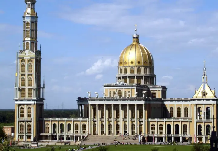 Bazylika w Licheniu z wysoką wieżą i złotą kopułą na tle błękitnego nieba.