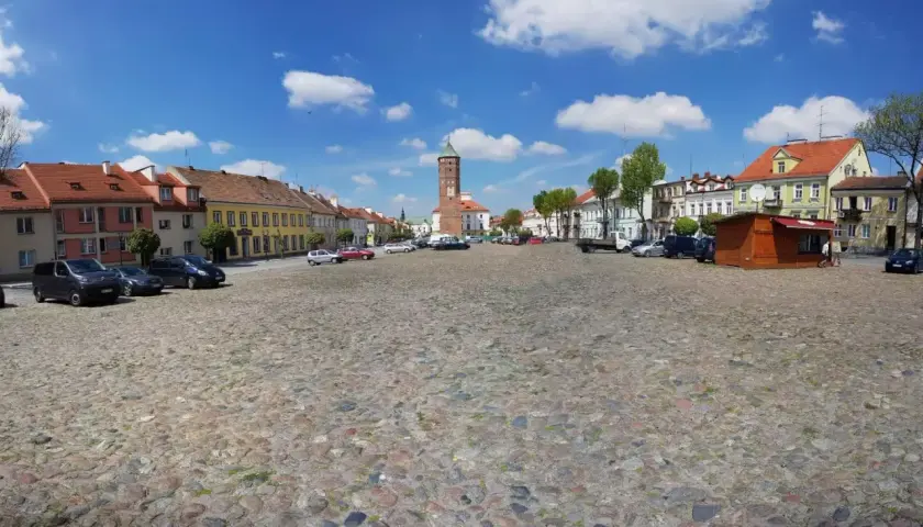 Rynek w Pułtusku z brukowaną nawierzchnią, kolorowymi kamienicami i charakterystyczną wieżą.